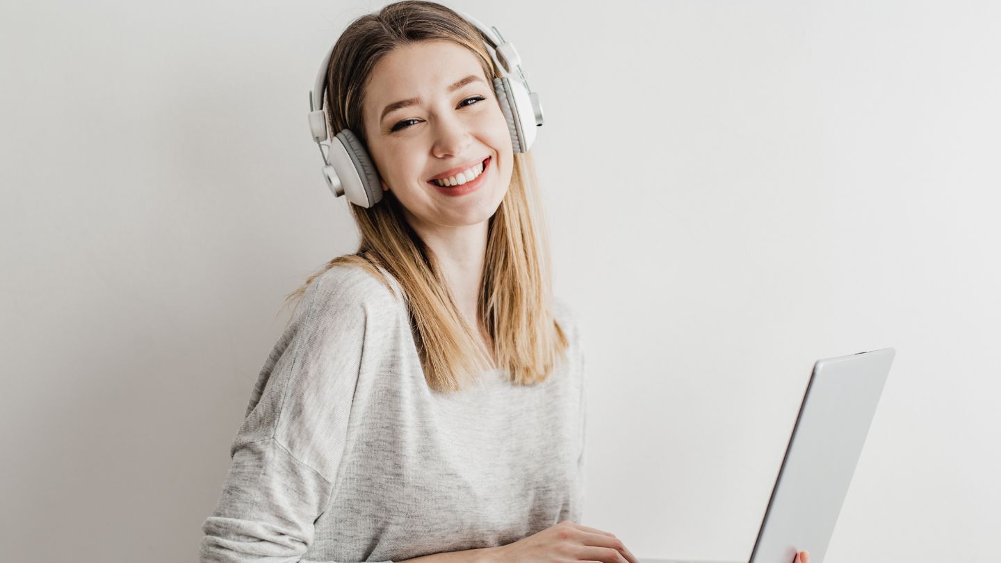 Woman Smiling With Headphones And A Laptop 
