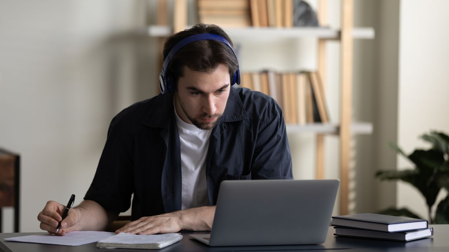 Man Studying Online with Headphones and Laptop
